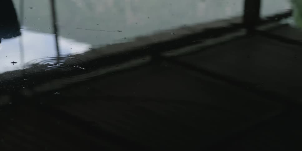 Light reflects on water as it ripples and moves and on droplets on the glass