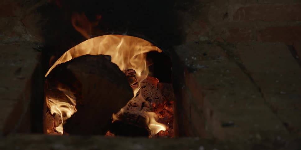 Large logs are burning in a roaring fire in an outdoor fireplace