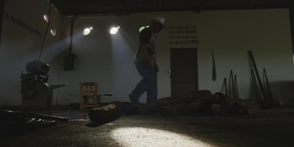 A farmer is working inside of a barn in the day time