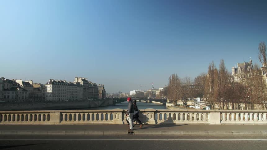 People walk across a bridge under a clear sky