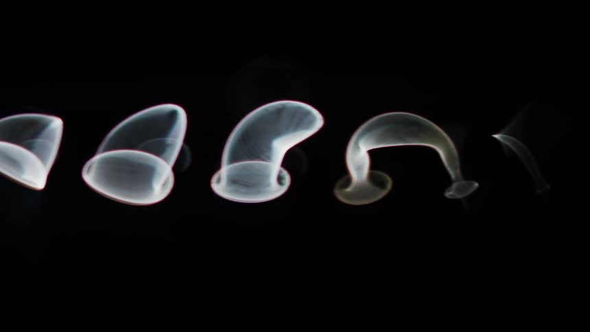 Smoke rings floating on black background