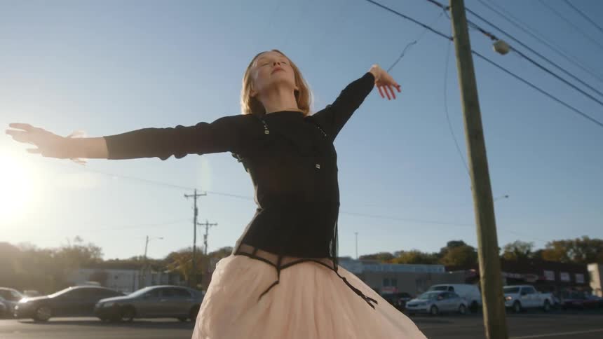 A young woman is dancing and posing for the camera downtown area