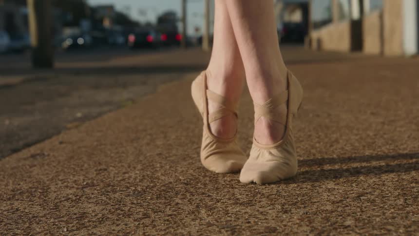 A female is dancing ballet outdoors in a city