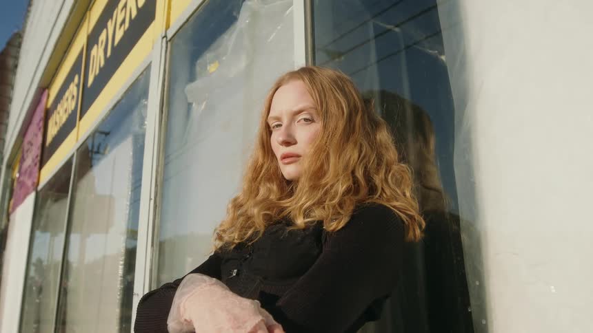 Young woman is outdoors and is posing for the camera