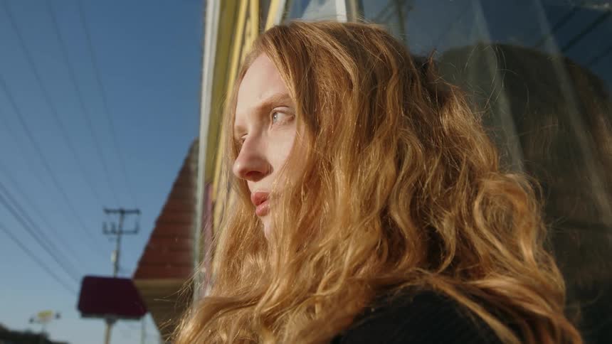Blonde woman leans against store window