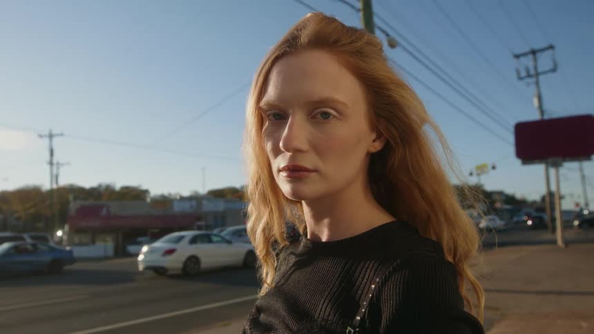 Young woman is standing outside and is posing for the camera