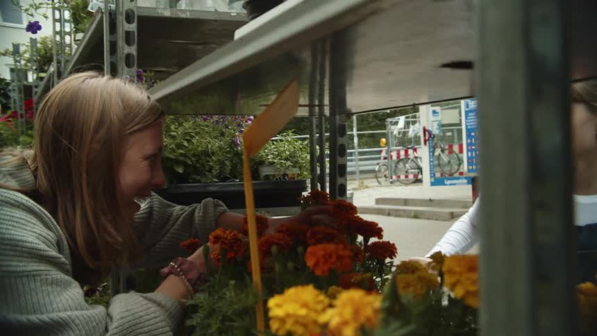 Mother and daughter smelling flower on the outdor shelfs of a store in a small town