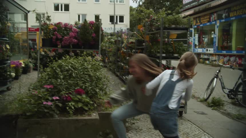 A woman and girl running between shelves with flowers
