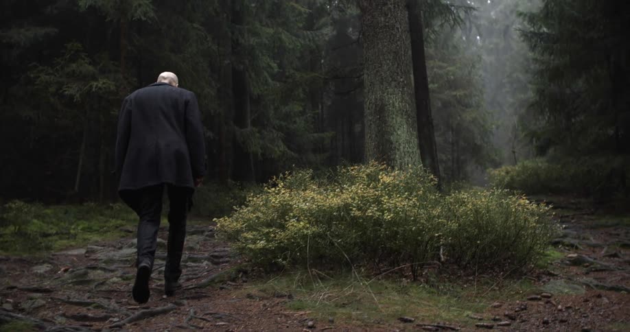 Elderly man in a suit walking up a path in the wilderness