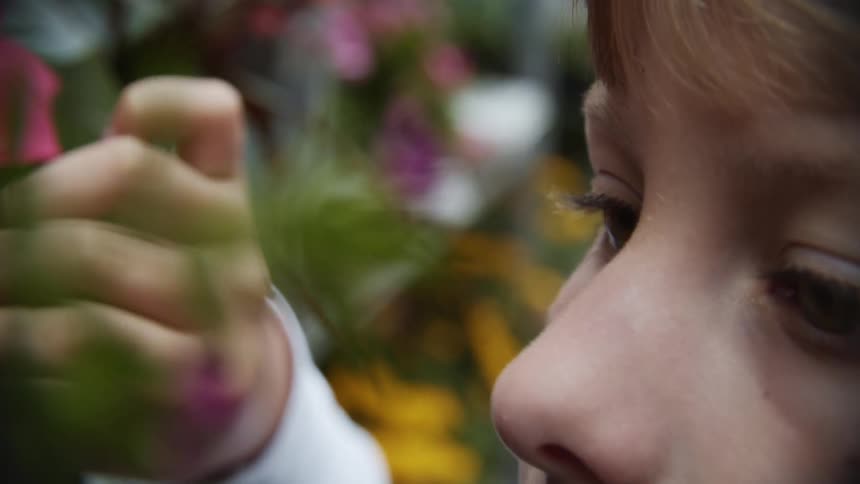 A young girl touching and looking at plants and flowers