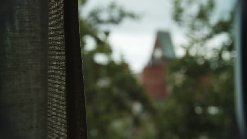 Out of focus footage of the tower of a church seen from the window of a house