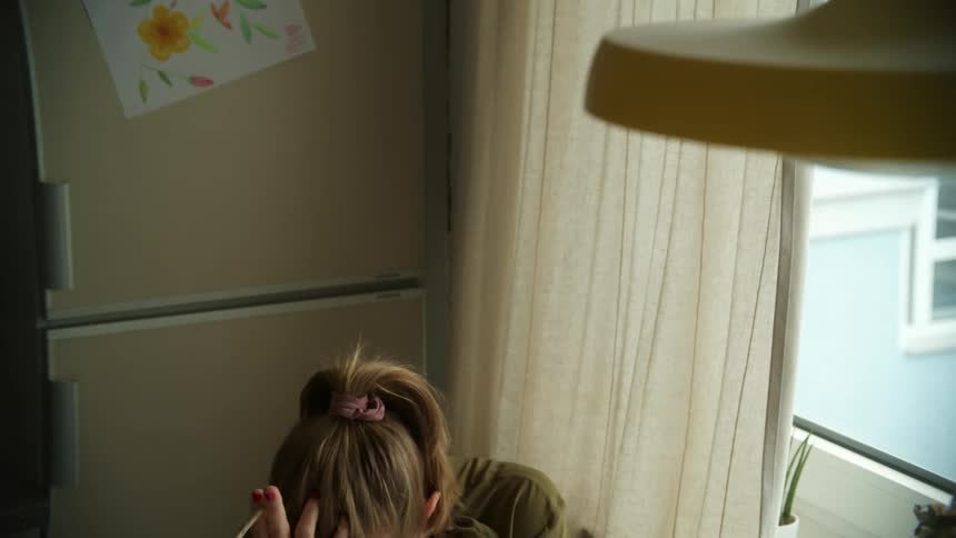 Nervous woman holding a cigarette sitting in kitchen looking out the window