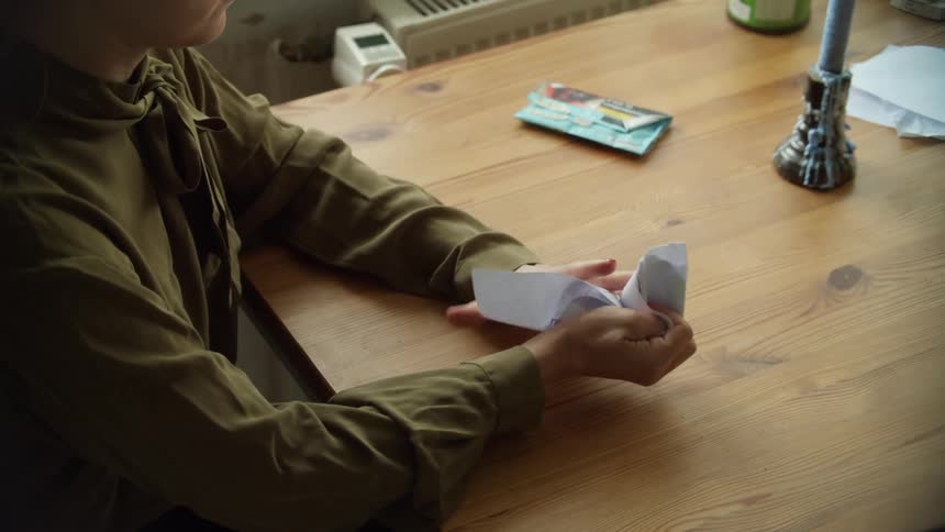 A person is sitting at a table and ripping a piece of paper