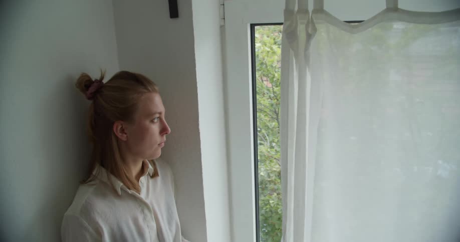 A woman standing in a room next to a window with curtains