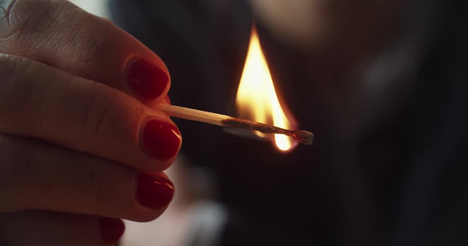 Woman holding a burning match puts it out blowing over it