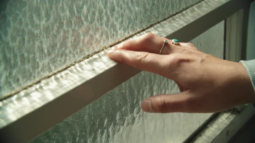 A person traces the window with her hand