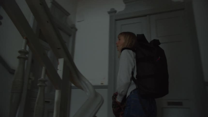 Young woman carrying a backpack walking up the stairs of a building