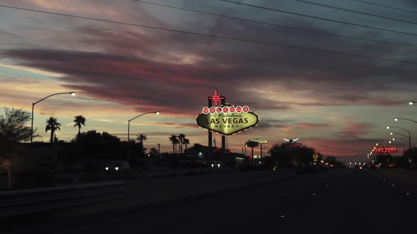 Moving past a city at dawn with bright signs