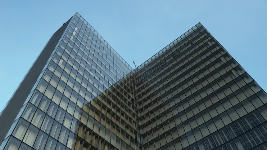 A glass high-rise stands against a clear blue sky