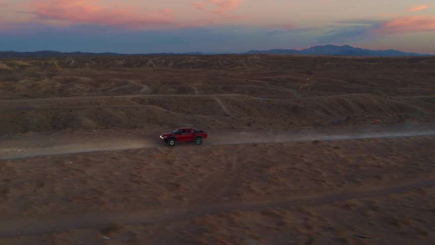 Tracking shot of racing truck at sunset with pink sky