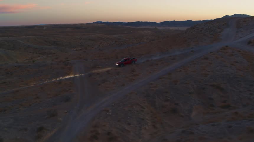 Red Baja Truck Drives Through Desert at Sunset