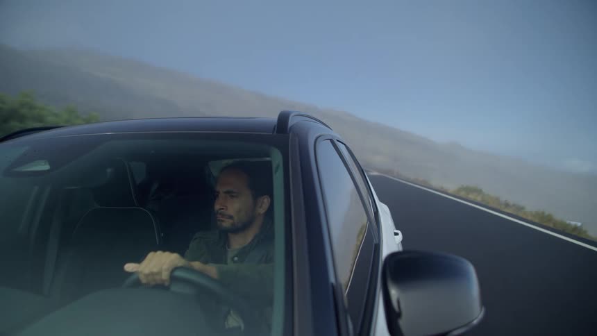 A man looks around as he drives his car down a street