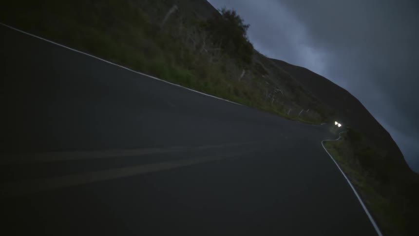 A car is driving down the road in the forest area