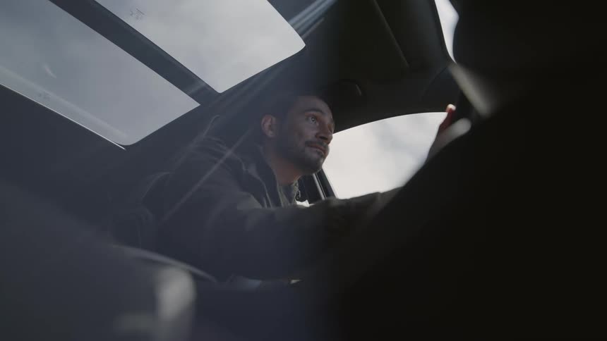 A man is driving an automobile and he looks around as he drives