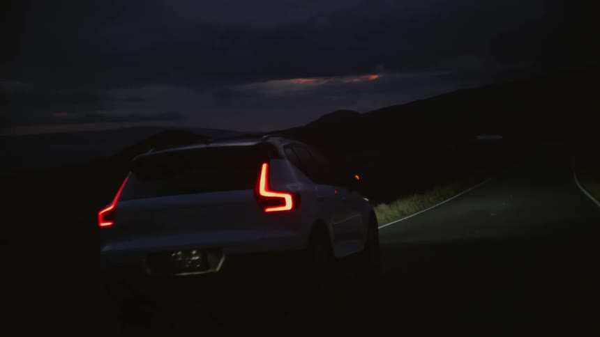A vehicle travels along a countryside road at night