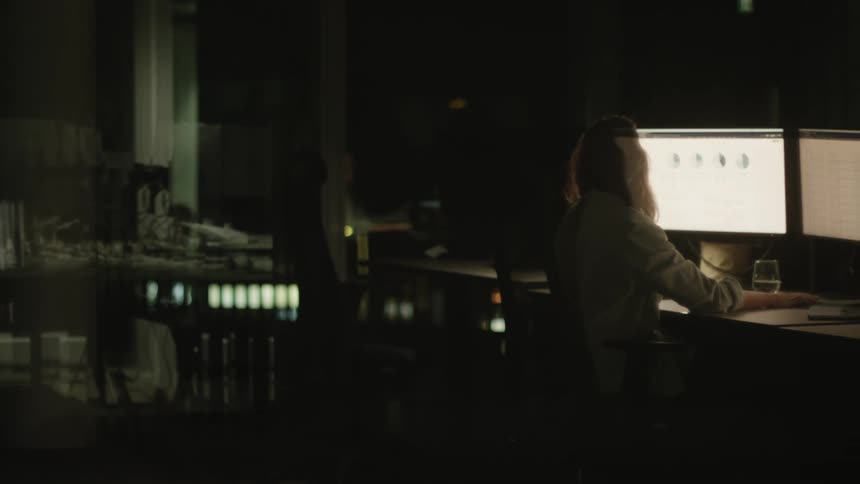 Woman with glasses and brown hair works on computers in the studio