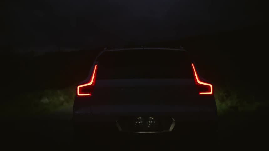 A car is driving down the road in the forest area at night time