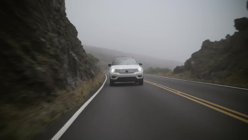 A white suv traveling on a remote road on a foggy day