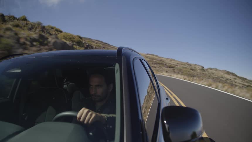 A male is driving a car through a remote area on a clear skies day