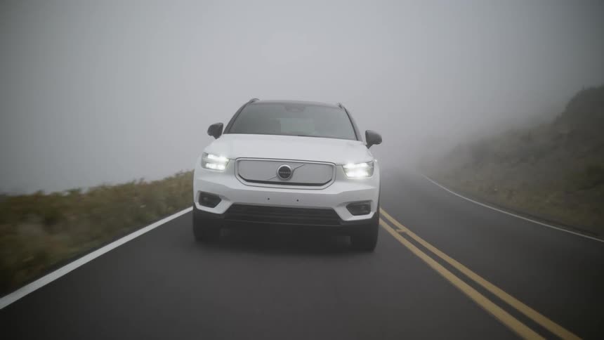 A white vehicle is driving down a foggy highway