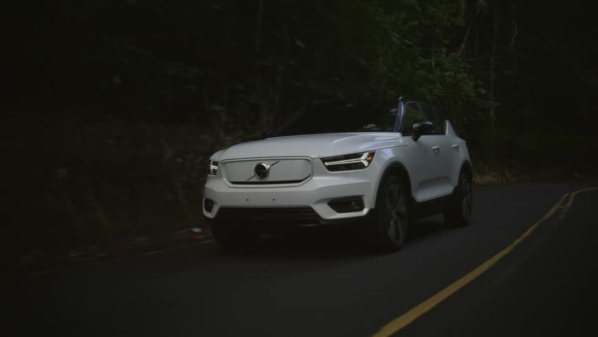 A car is driving down the road around the forest area