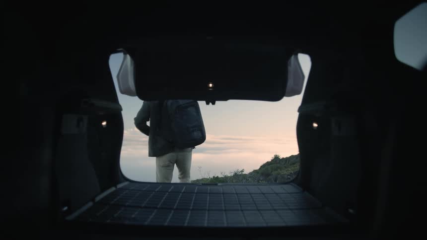 A man gets his backpack out of his vehicle while parked in a canyon