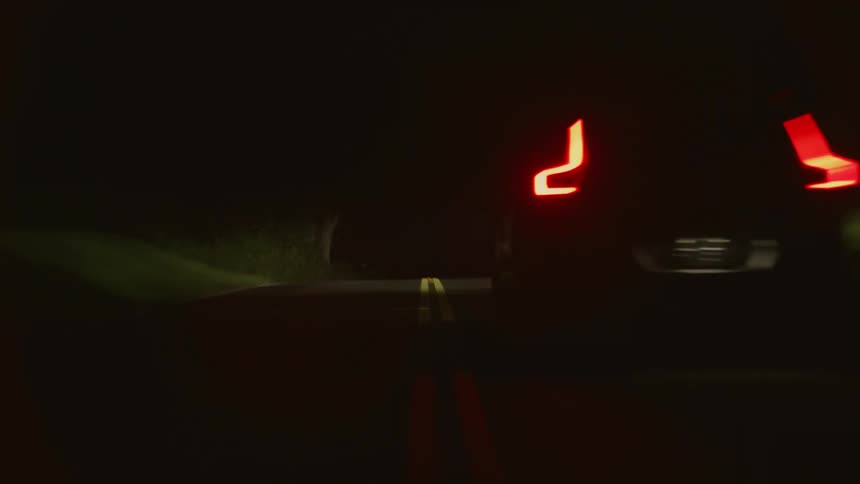 The headlights of an automobile illuminate the road as it travels in the darkness
