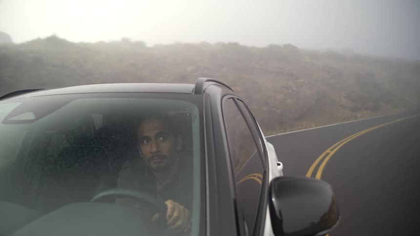 Man passes truck going the opposite way as he drives along curving highway on very foggy day