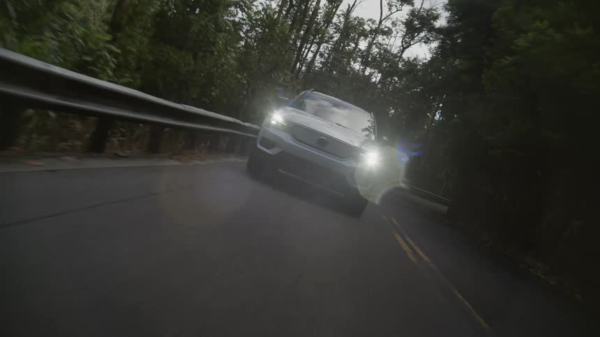 White 4x4 car drives on highway through forest