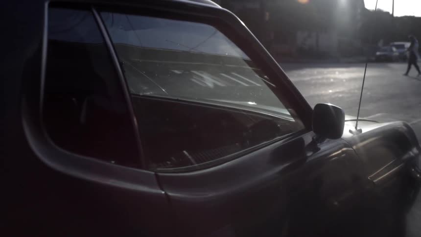 A car is parked on the street as a person crosses