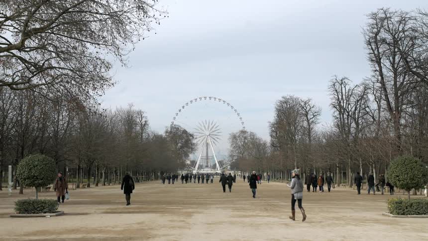A group of people walk toward a ferris wheel