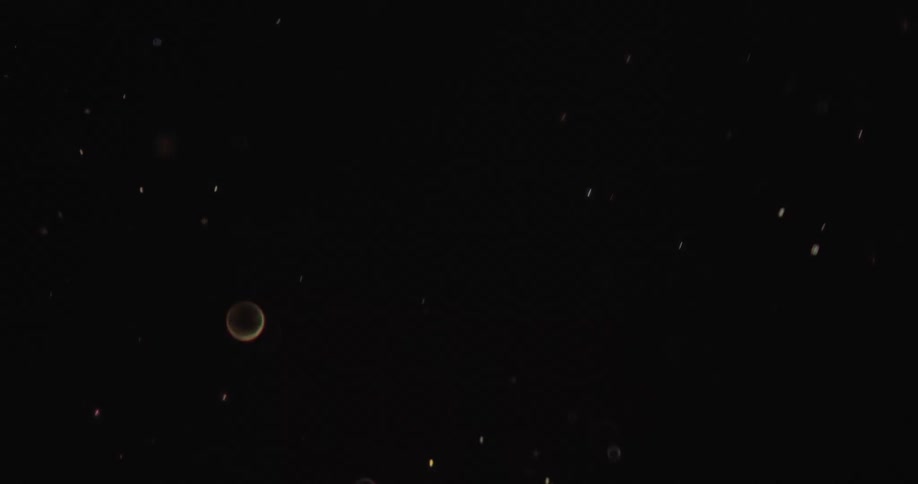 Close up of sparks or bright particles flying in front of a dark background