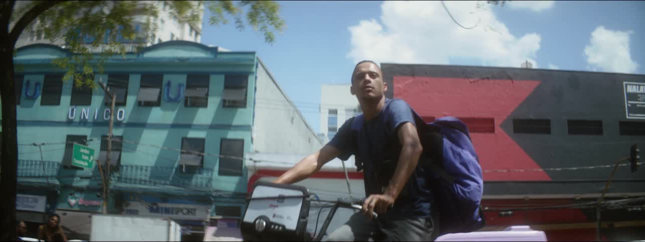 A man stops his bicycle to look at buildings in a colorful neighborhood
