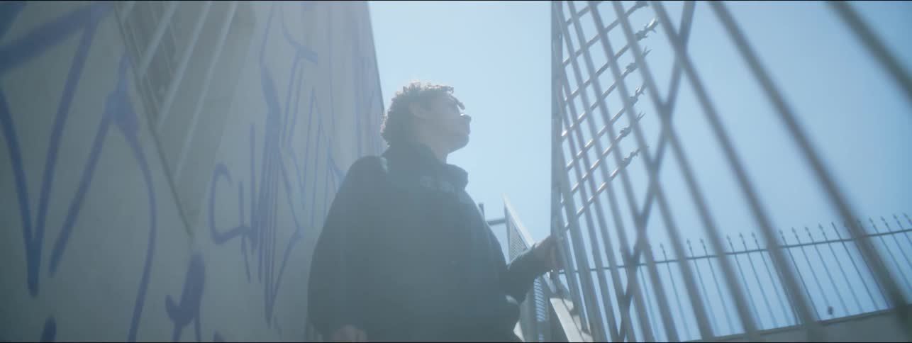 A male holds on to a railing and looks around