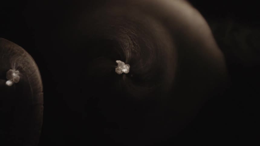 Spining particles slowly spiraling leaving a trail of waves and ripples behind