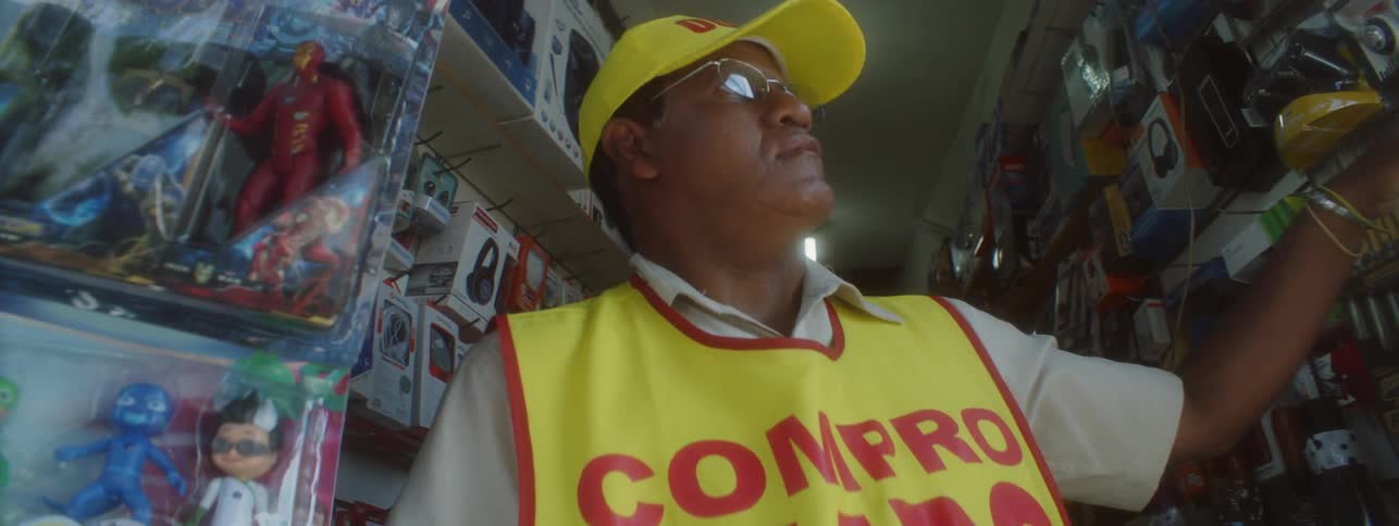 An employee in an electronic shop stands in front of a fan looking up outside to the street