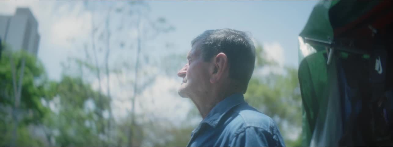 An elderly man is standing outside in the downtown area