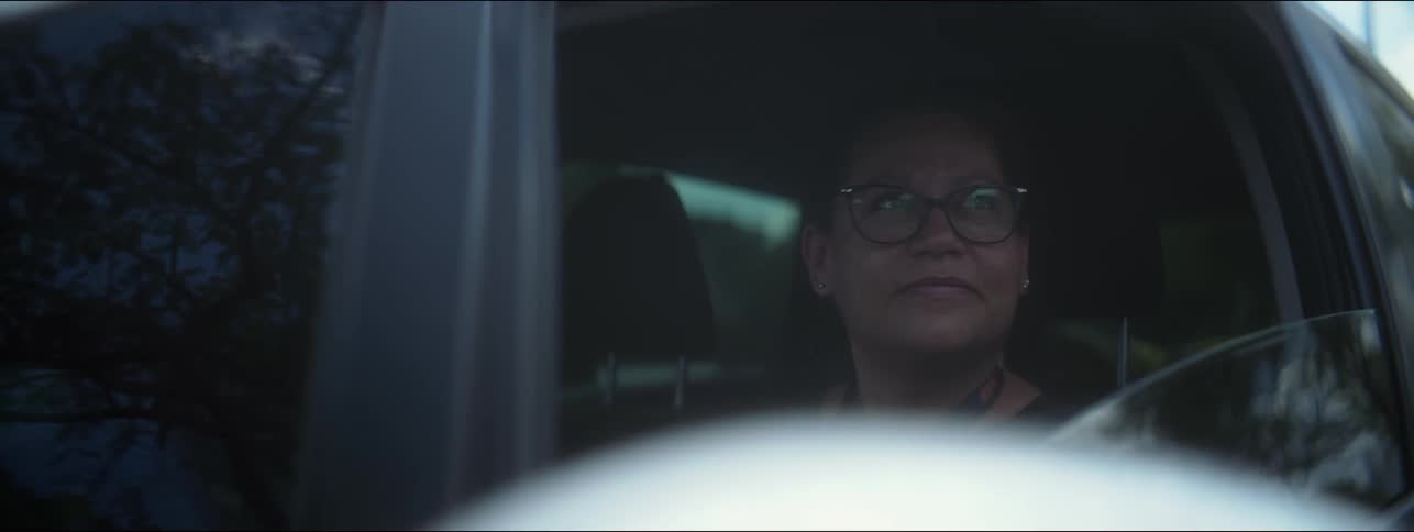 A vehicle window rolls down revealing a female looking out intrigued at the view