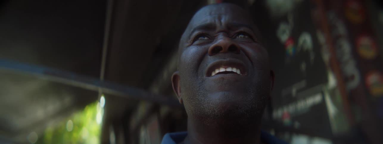 A man is standing outside a small business looking up surprised
