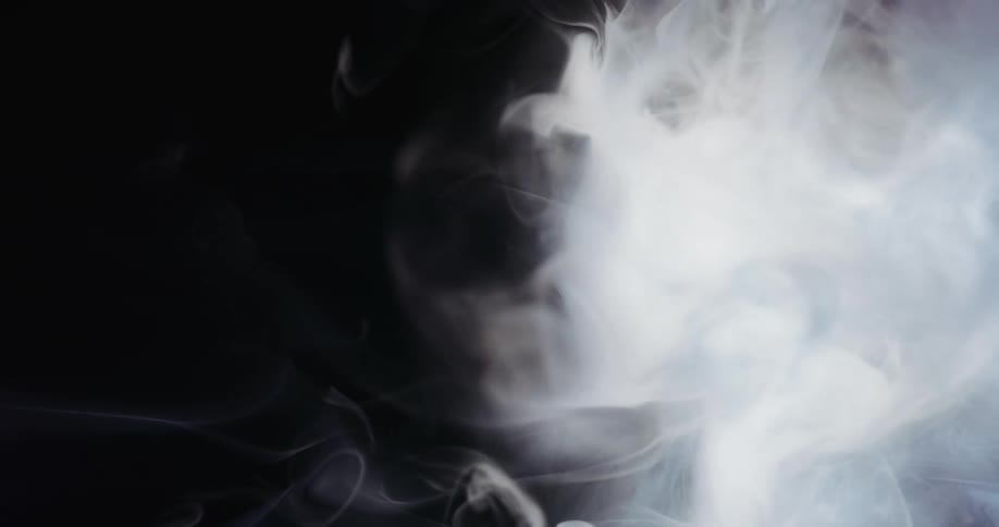 A white smokey substance moves as wisps stretch across the darkness